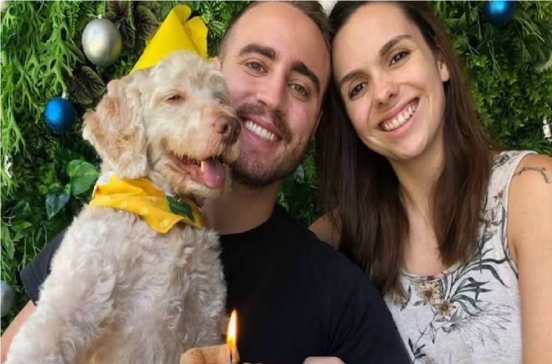 Foto do cachorro em aniversário ao lado de seus tutores