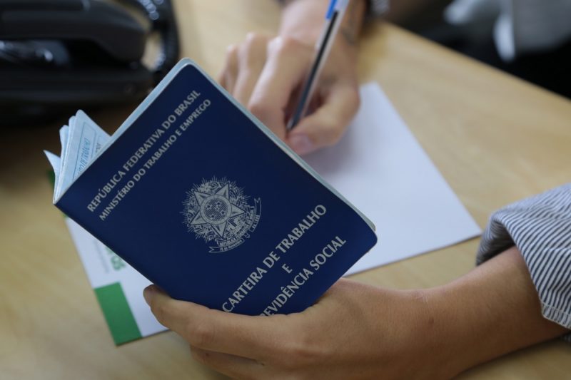 Homem buscando emprego com a carteira de trabalho na mão 