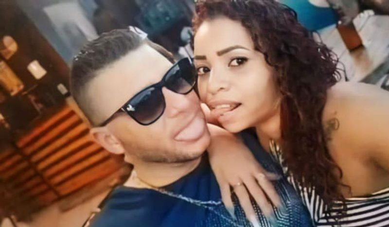 Homem e esposa, ele teve o pênis decepado por ela em SP - Homem branco e mulher negra sentados juntos e com as línguas para fora como se fossem se tocar