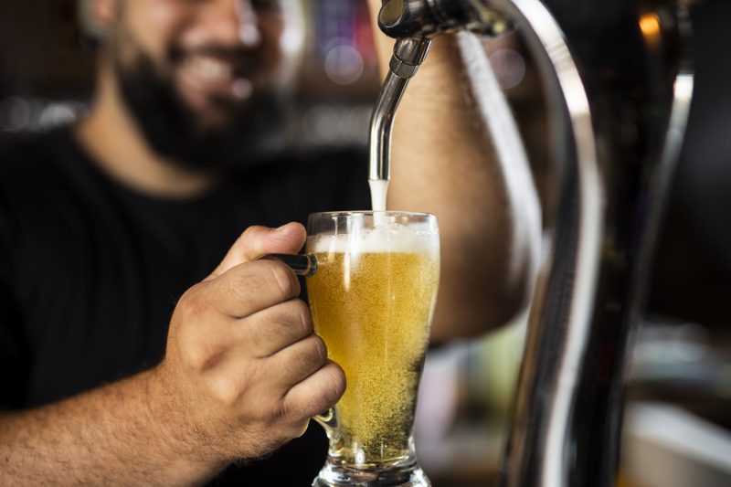 Pessoa enchendo copo com cerveja