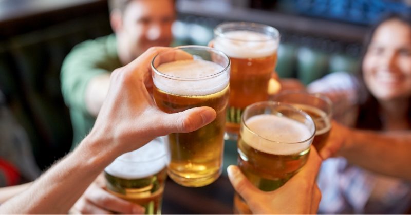 na foto aparece uma comemoração de happy hour com cerveja, que ajuda a piorar a síndrome do intestino irritável