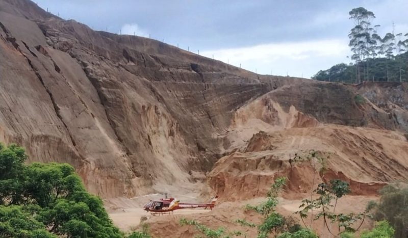 Criança é ejetada e pai fica em estado grave após carro capotar de ribanceira de 15m em SC, foto mostra ribanceira de terra com helicóptero dos bombeiros embaixo