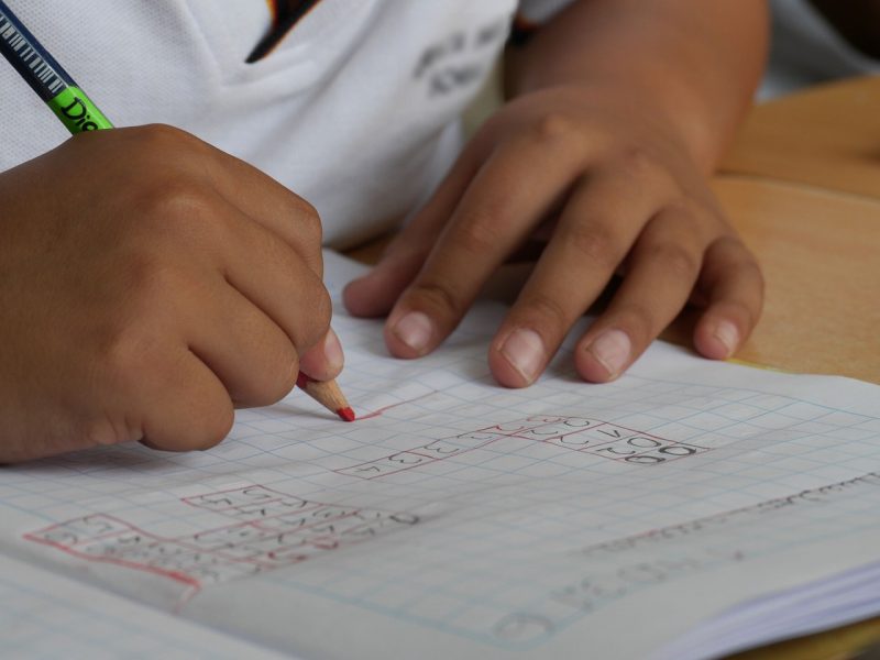 Mãos de uma criança negra fazendo as tarefas em caderno escolar 