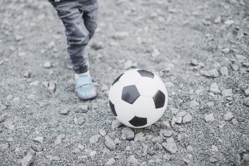 Foto ilustrativa de criança jogando futebol. Foi ao brincar na rua que menino de 9 anos acabou levando chutes na cabeça