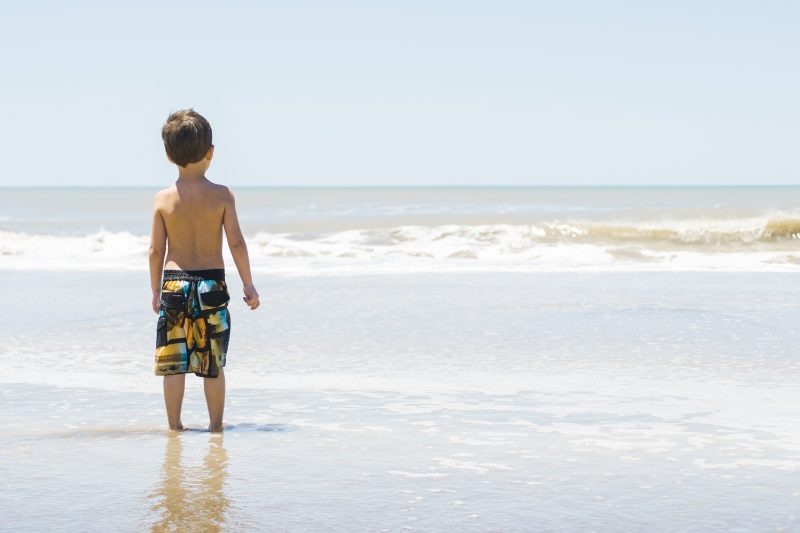 Imagem ilustrativa de criança olhando para a correnteza do mar 