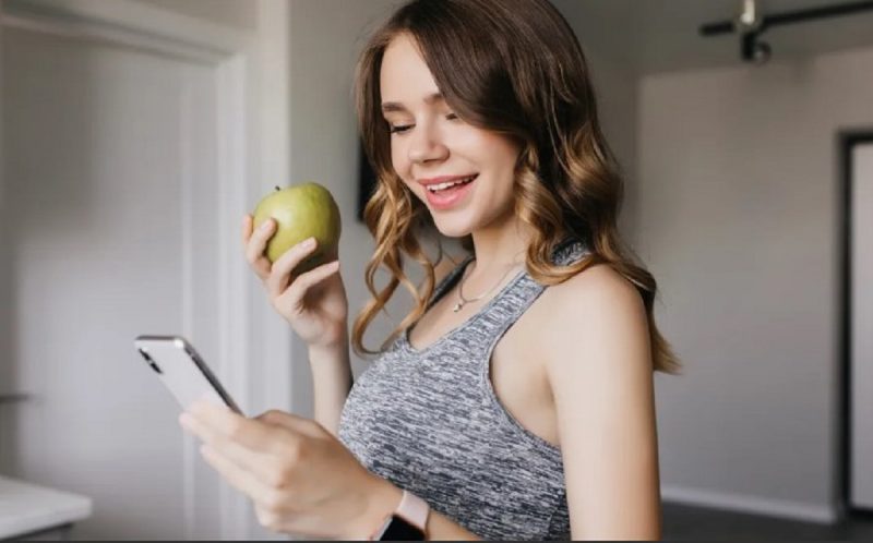 na foto aparece uma mulher comendo uma maça e lendo dieta para derreter gordura