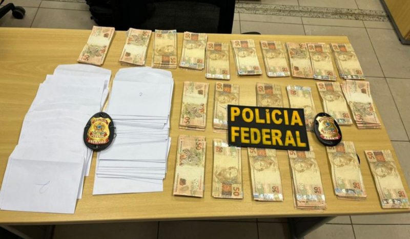 Dois pastores são presos suspeitos de compra de votos em Manaus, foto mostra notas de cinquenta separadas em montes e papeís, com o nome da polícia federal por cima