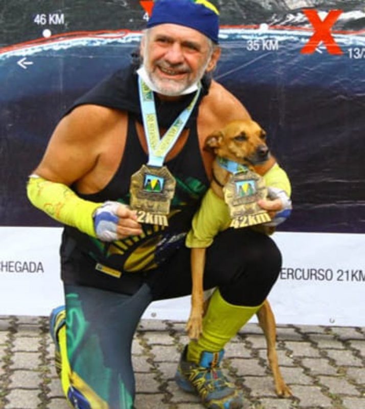 Registro de Neumann e cachorro corredor com medalhas em competição de 42 km