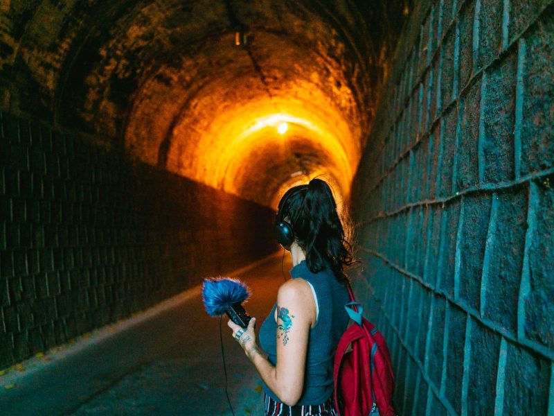 A imagem mostra uma mulher em um túnel com um gravador de áudio.