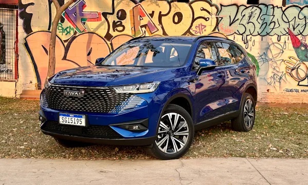 GWM Haval H6 na cor azul estacionado em frente de muro grafitado