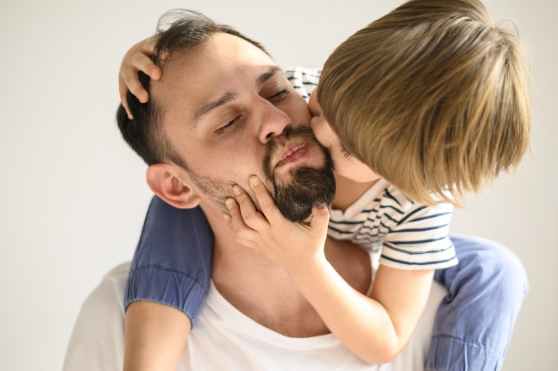 Filho beijando o pai na bochecha 