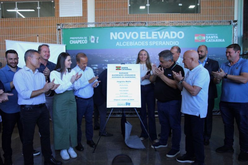 Governador Jorginho Mello ao lado do prefeito de Chapecó João Rodrigues e demais autoridades políticas batendo palmas ao lado da placa de inauguração do elevado da bandeira 