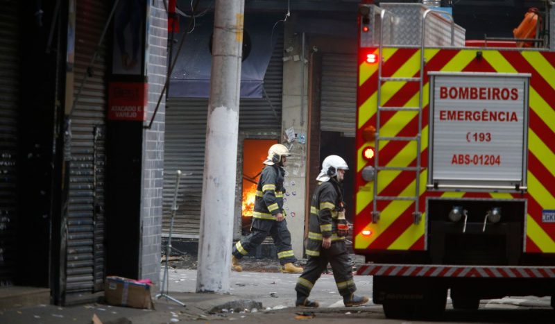 Incêndio no Brás - dois agentes dos bombeiros andando na rua ao lado de viatura dos bombeiros de São Paulo durante ocorrência