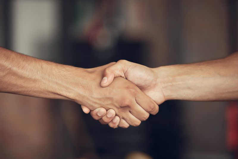 na foto aparece um aperto de mão firme entre duas pessoas se cumprimentando