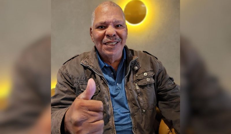 Maguila, ex-pugilista morreu aos 66 anos - homem negro, de cabelos curtos e grisalhos usa camisa azul e jaqueta marrom por cima, sorrindo e fazendo sinal de legal