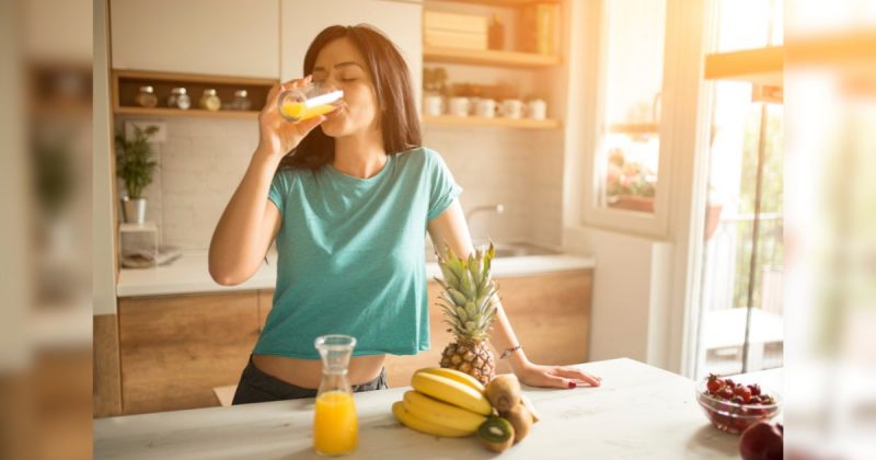 Pessoa tomando suco com frutas em mesa