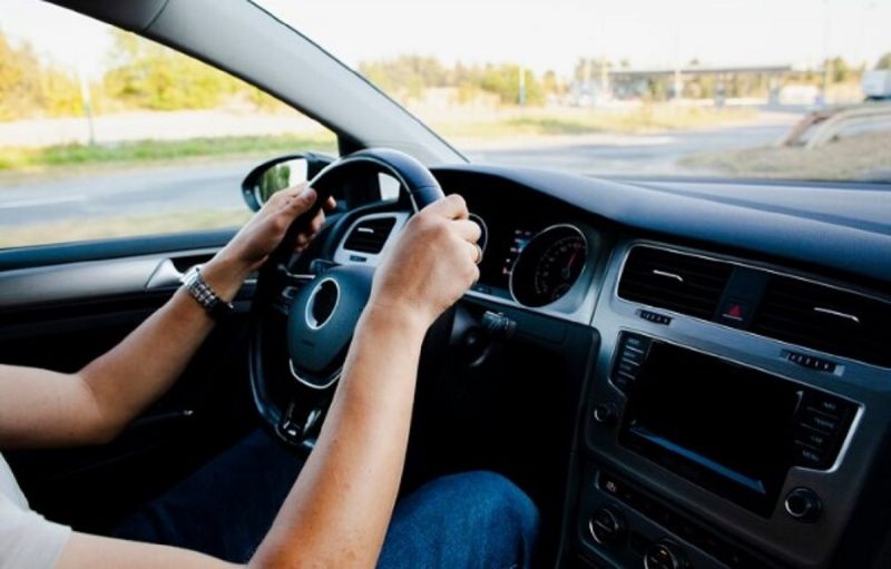 aparece as mãos no volante e mulher é quem dirige melhor conduzindo o carro 