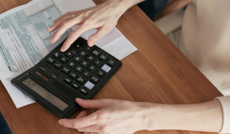 mulheres responsáveis pelo sustento da casa, foto mostra mulher fazendo contas em uma calculadora com boleto em baixo