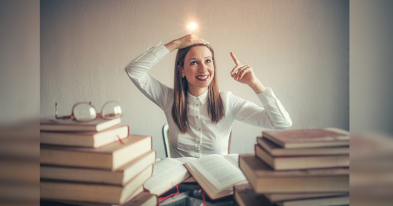 Mulher em meio aos livros com uma lampada na cabeça