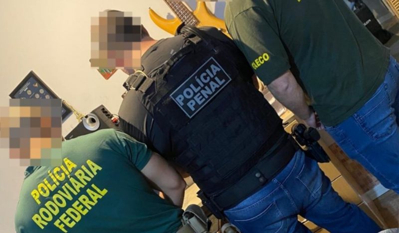 Operação que prendeu suspeitos de armazenar pornografia infantil, foto mostra policiais penal, rodoviário federal e um agente do gaeco fardados e de costas