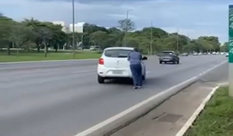 passageiro aparece empurrando carro branco de motorista de aplicativo