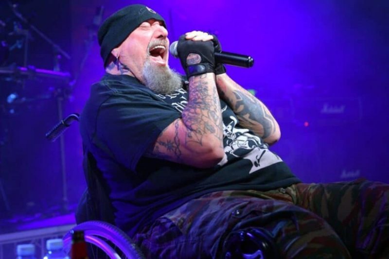 Músico Paul Di'Anno canta sentado em uma cadeira de rodas