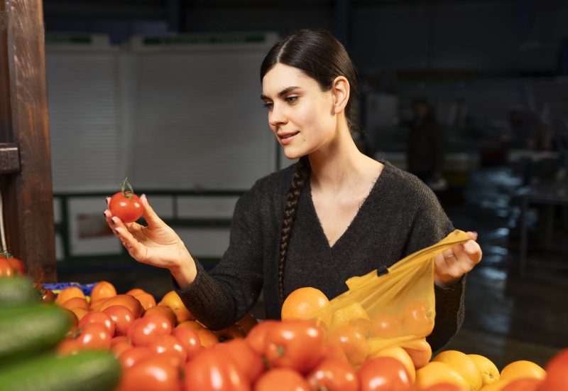 Mulher escolhendo tomates na feira