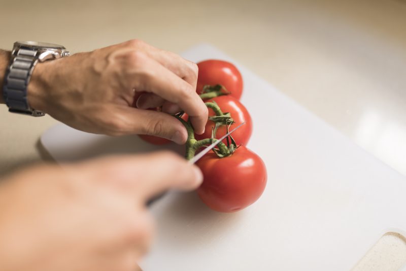 Homem cortando tomates