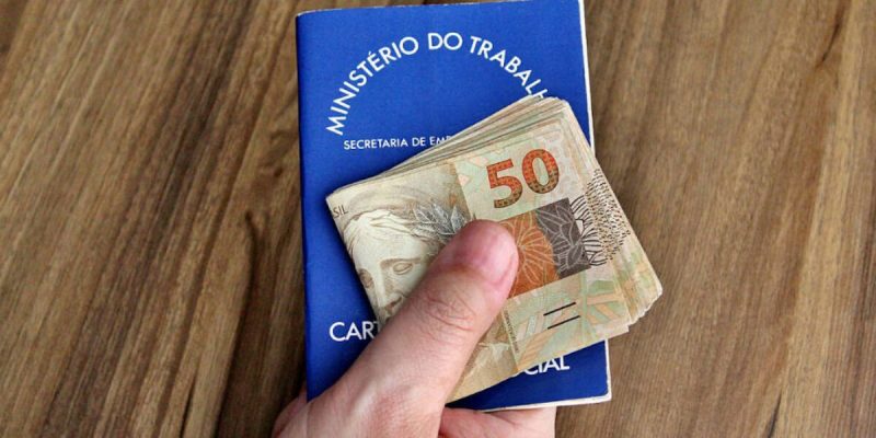 Carteira de trabalho com salário na mão