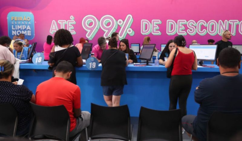 Pessoas negociando dívidas em balcão do Feirão Limpa Nome do Serasa