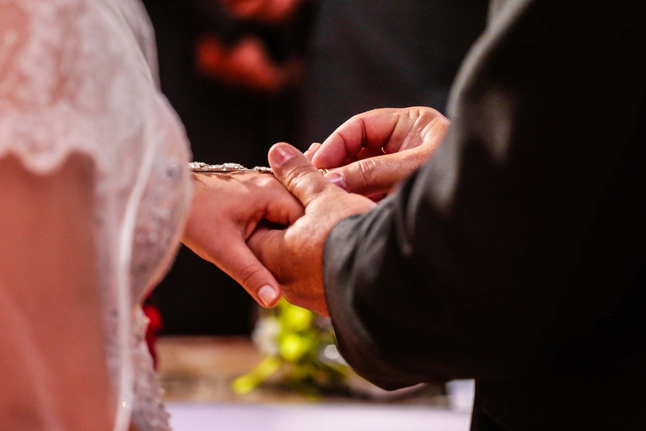 Foto de um homem colocando aliança na mão de uma mulher para ilustrar matéria sobre casamento coletivo em Criciúma