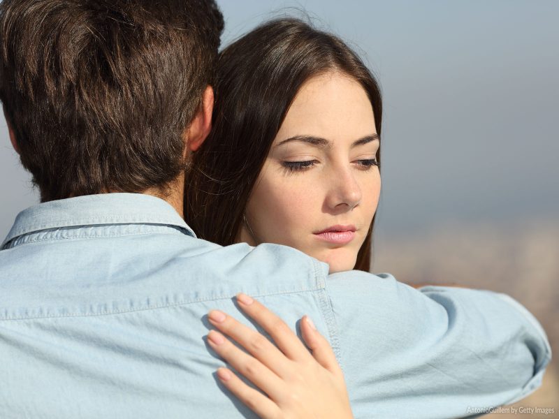 Mulher de cara feia abraçando um homem