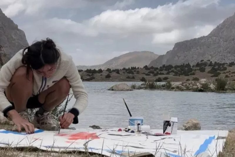 Artista fazendo desenho na beira de um lago