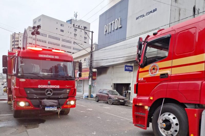 A imagem mostra a loja que pegou fogo em Brusque e carros de bombeiros.