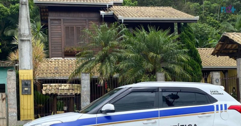 Imagem da fachada da casa de casal assassinado em Itajaí com carro da polícia científica na frente 