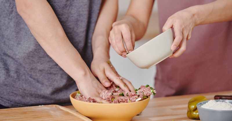 Duas pessoas cuidando e preparando carne moída