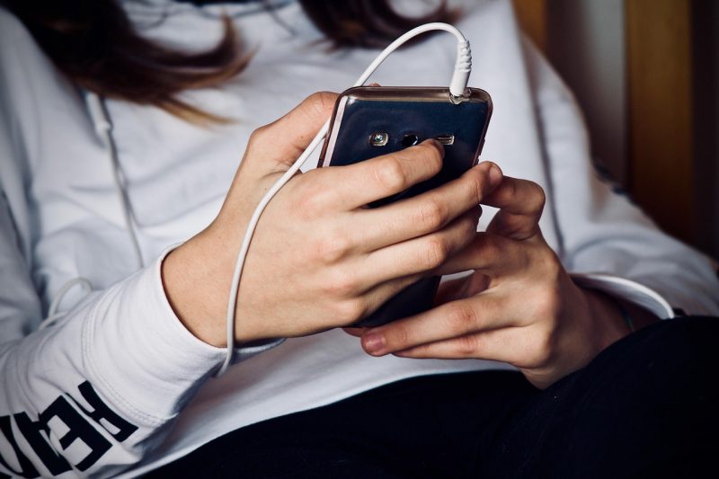 Pessoa mexendo em celular com fones de ouvido