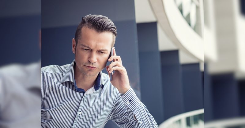 Homem em celular com rosto sério