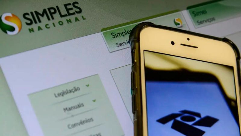 Celular em frente ao site do Simples Nacional 