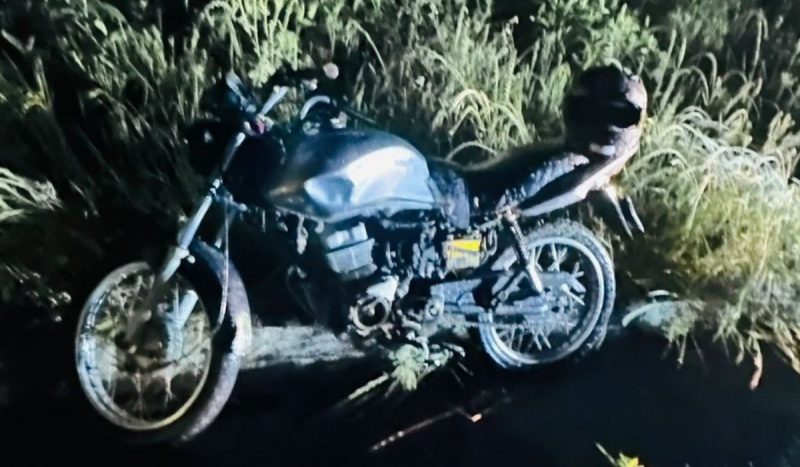 criança de 12 anos e homem de 21 se acidentam, foto mostra motocicleta preta em pé no acostamento da rodovia com capacete na traseira