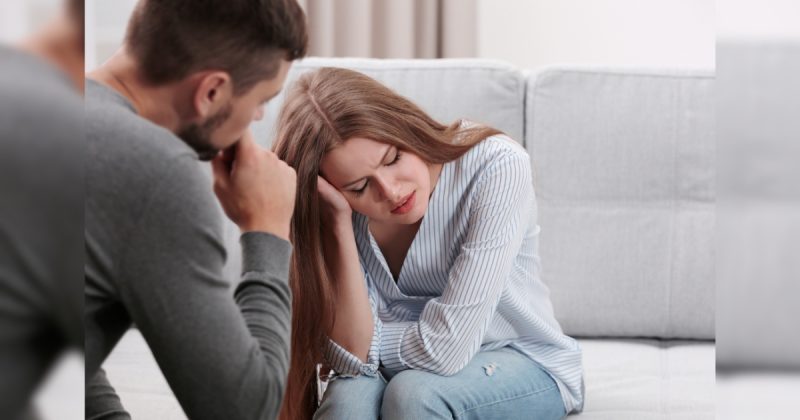 Casal de frente um para o outro, com mulher com mão no cabelo e homem com mão no queixo