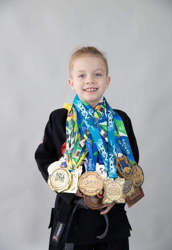 Heithor segurando suas medalhas conquistadas no Jiu-Jitsu