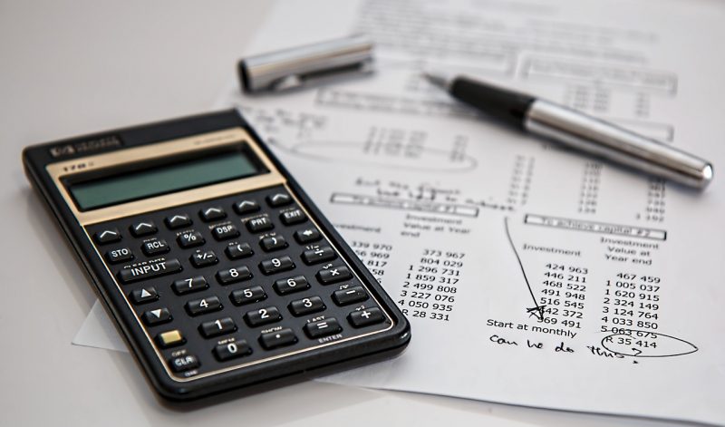 Calculadora em cima de uma mesa com caneta e papel 