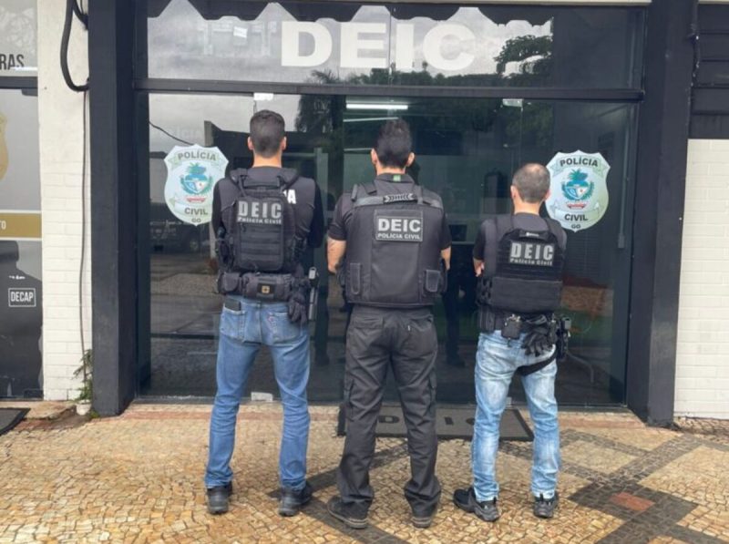 Foto mostra policiais civis que investigaram a invasão de contas bancárias de costas