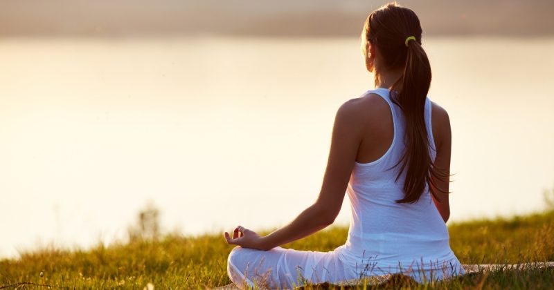 Mulher meditando olhando para praia