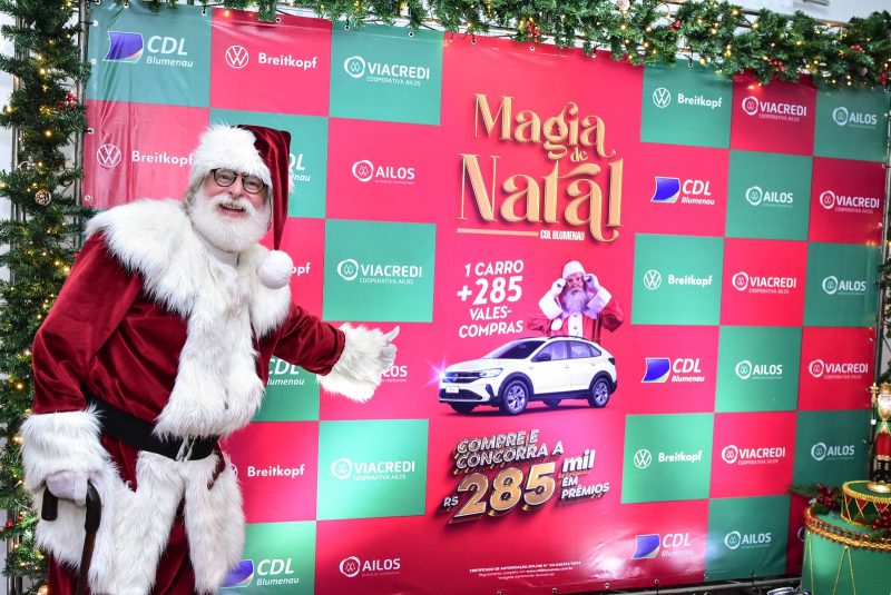 Papai Noel apontando para cartaz de campanha de Natal 