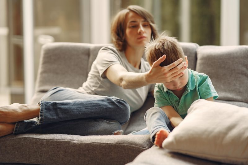 Mãe cuidando do filho em um sofá 