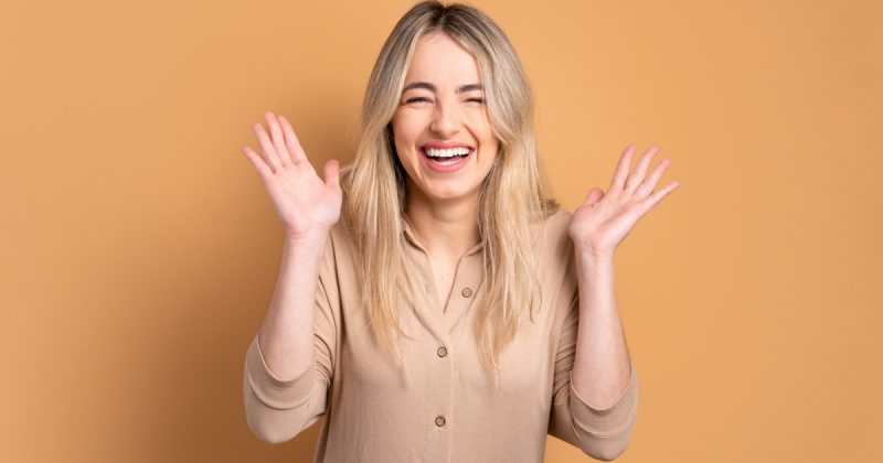 Mulher rindo com mãos para o alto