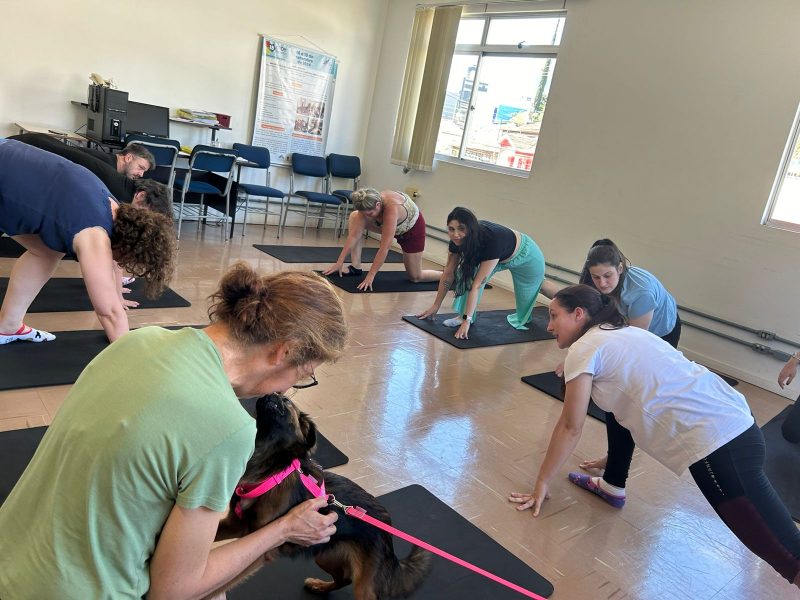 Paciente do projeto de terapia com pets abraçando cachorro durante aula de ioga