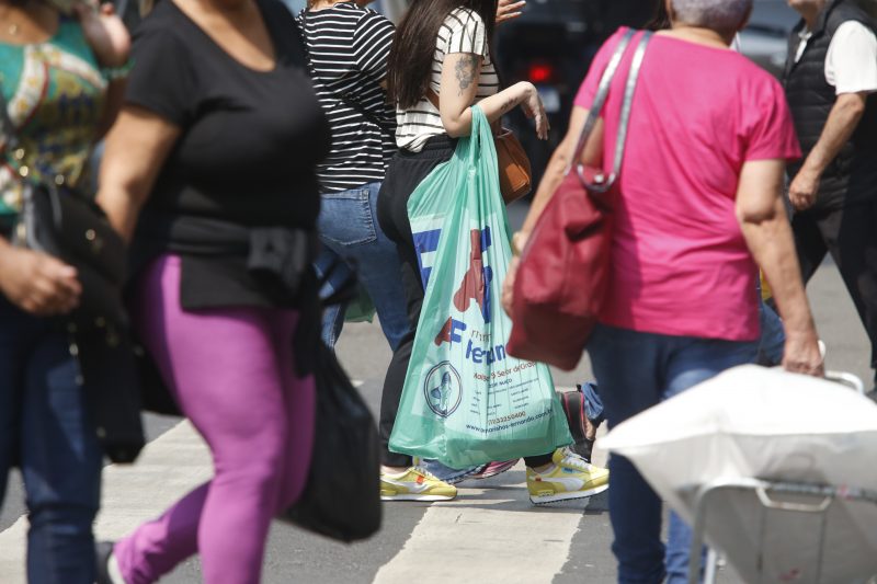 Rua movimentada com pessoas passando com sacolas de compras 